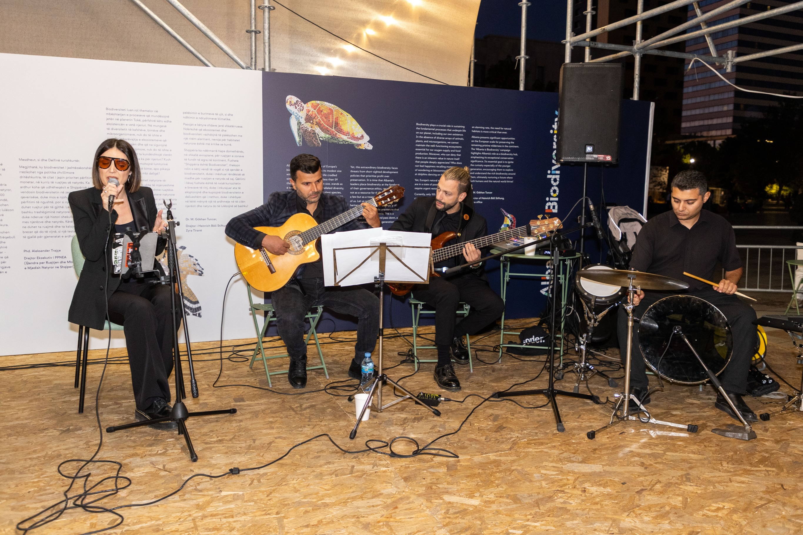 Grup muzikor me një këngëtare, dy kitaristë dhe një baterist duke performuar.